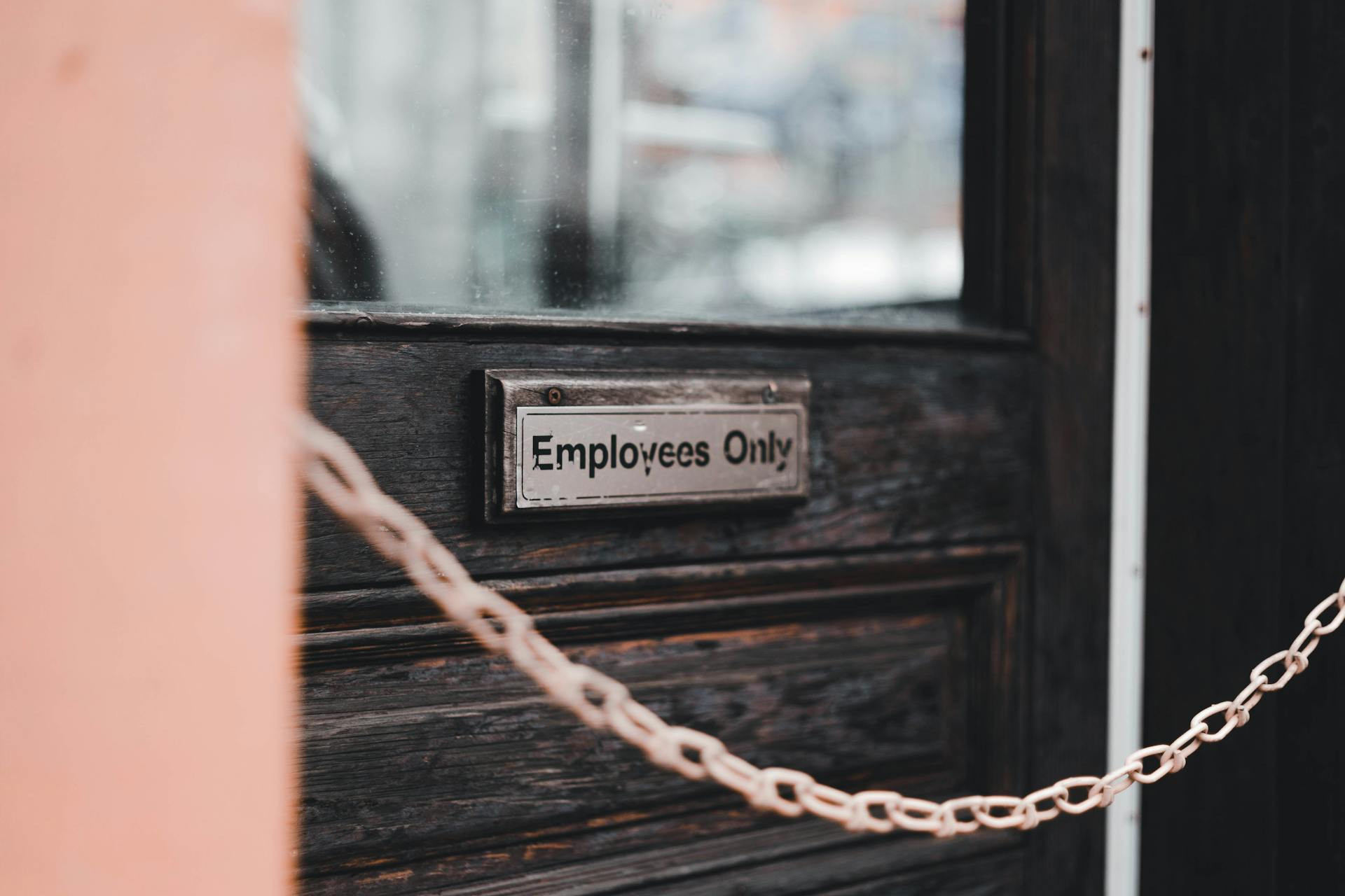 A sign reading "Employees Only" is mounted on a dark wooden door, with a metal chain stretched across the entrance.