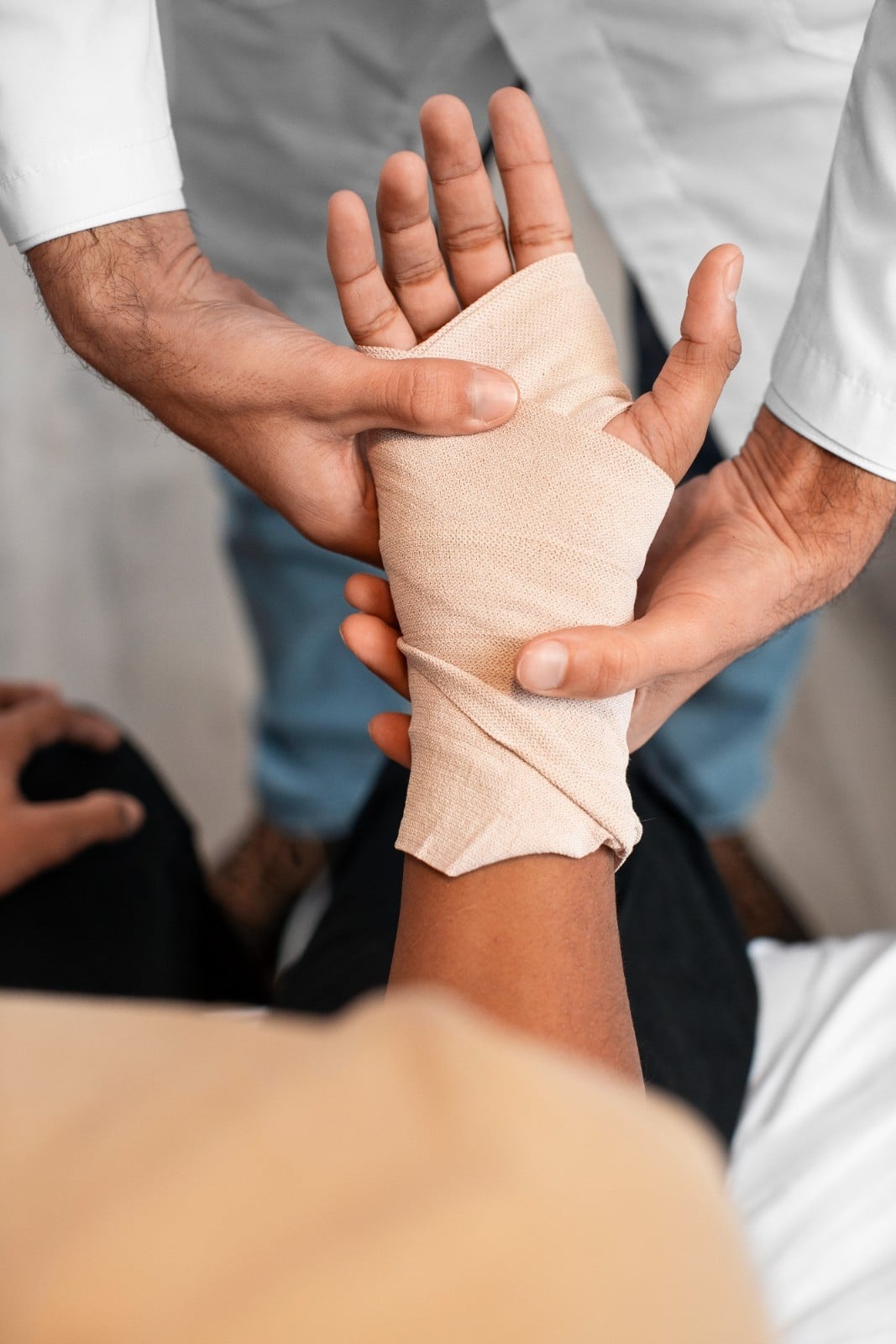 A medical professional wraps a patient’s injured hand with a bandage.