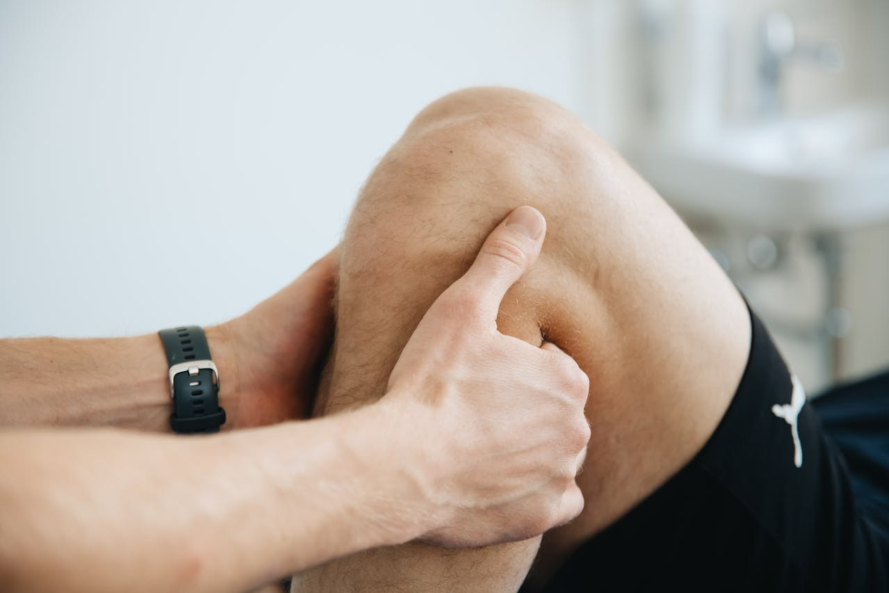 A person holds and presses the side of their right knee, possibly indicating pain or discomfort.